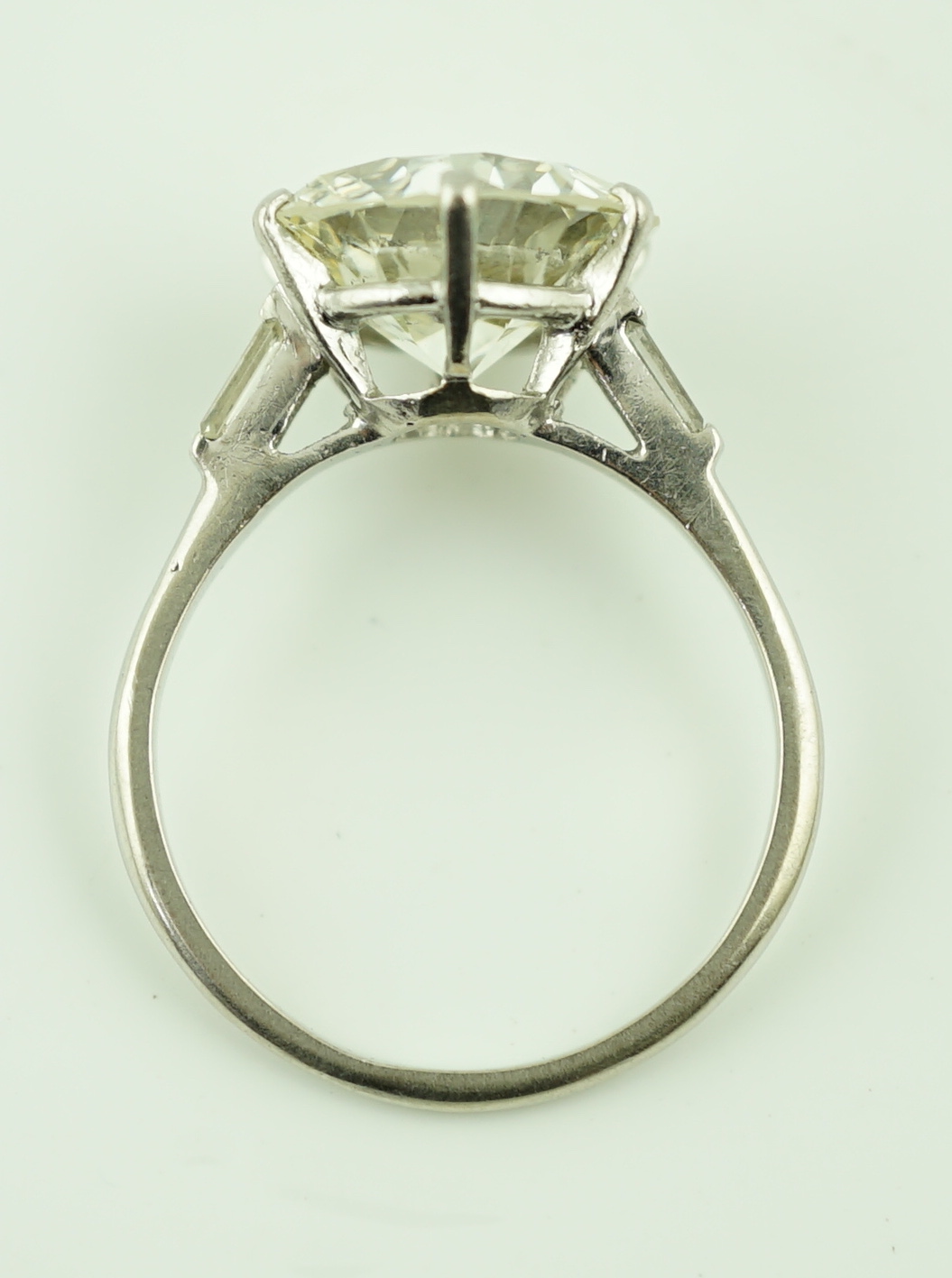 A platinum and single stone diamond set ring, with baguette cut diamond set shoulders
